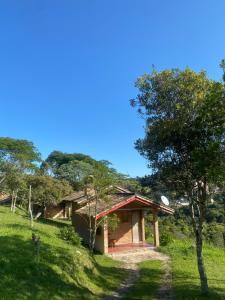 a building on a grassy hill with a tree at Pousada Chalés Vale do Sol in Conceição da Ibitipoca