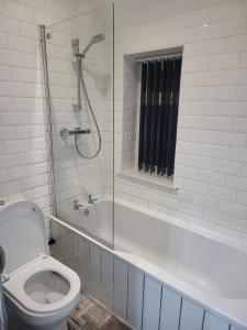 La salle de bains est pourvue de toilettes et d'une baignoire avec douche. dans l'établissement Getaway Home in Manchester, à Manchester