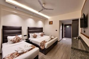 a hotel room with two beds and a flat screen tv at Click Sunburry Hotel Katra in Katra