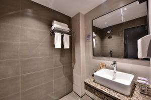 een badkamer met een wastafel en een spiegel bij Click Sunburry Hotel Katra in Katra