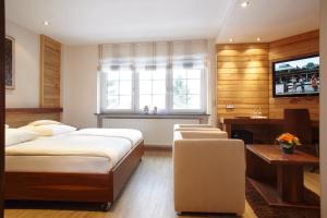 a bedroom with two beds and a desk and a television at Sporthotel Leweck in Lipperscheid