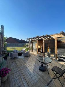 un patio con sillas y mesas en una terraza de madera en La bulle à bonheur - Spa privatif 