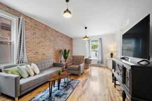 - un salon avec un canapé et un mur en briques dans l'établissement DUPLEX FOR GROUP STAY_MONT-ROYAL, à Montréal