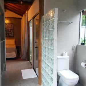 a bathroom with a toilet and a room with a bed at Pousada Recanto Jota Ge in Paraty