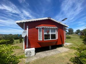 Chacao Viejo的住宿－Cabañas Los Queltehues，一间红色的小房子,设有窗户和风扇