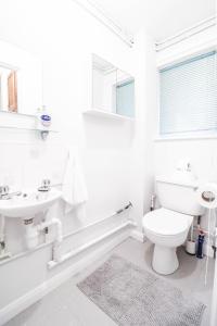 a white bathroom with a toilet and a sink at Contractor House by BBC Studios - Free parking! in Borehamwood