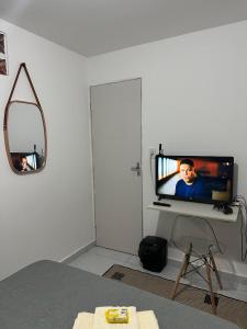 Habitación con TV y espejo en la pared. en Aero-Quarto Aconchegante, en Bayeux