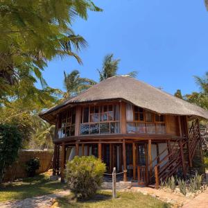 un edificio con techo de paja y un árbol en Samara Lodge, en Vilanculos