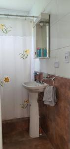 ein Badezimmer mit einem weißen Waschbecken und einem Spiegel in der Unterkunft Casa con PILETA, PARRILLA y cochera cubierta in Chascomús