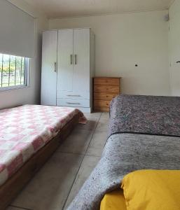 1 Schlafzimmer mit 2 Betten, einem Schrank und einem Fenster in der Unterkunft Casa con PILETA, PARRILLA y cochera cubierta in Chascomús