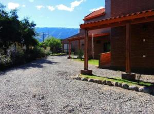 a gravel driveway next to a building with a mountain in the background at Complejo los Espinillos de Merlo in Merlo