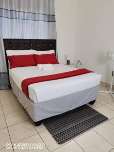een slaapkamer met een groot bed met rode kussens bij Mosas Home in Serowe