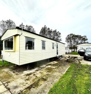 a small white trailer parked in a parking lot at Goldflinch - 3 bedroom (8 birth) caravan Sand Le Mere in Waxholme