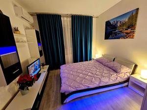 ein Schlafzimmer mit einem lila Bett und einem Schreibtisch mit einem TV in der Unterkunft Garsoniera Residence Militari in Chiajna