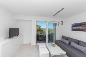 a white living room with a couch and a tv at Apartments M&A 2 in Makarska