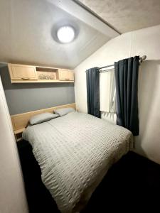 a small bedroom with a bed and a window at Goldflinch - 3 bedroom (8 birth) caravan Sand Le Mere in Waxholme