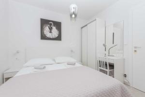 a white bedroom with two beds and a desk at Apartments M&A 2 in Makarska