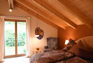 a bedroom with a bed and a window with a chair at Chalet Zauberberg in Zwiesel
