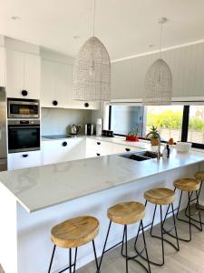 a kitchen with a large white counter and stools at The Beach House @ Primrose Sands in Primrose Sands