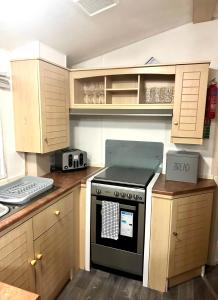 a kitchen with a stove and wooden cabinets at Goldflinch - 3 bedroom (8 birth) caravan Sand Le Mere in Waxholme
