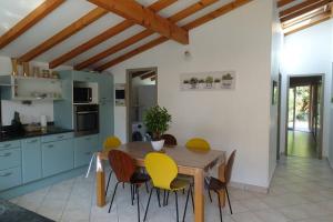 een keuken met een houten tafel en gele stoelen bij Villa au bord de la mer, piscine chauffée 9x4 in Labenne