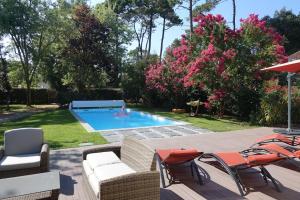 een achtertuin met een zwembad met stoelen en mensen in het water bij Villa au bord de la mer, piscine chauffée 9x4 in Labenne