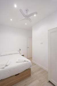 - une chambre blanche avec un lit et un ventilateur de plafond dans l'établissement Chic Central Madrid, à Madrid