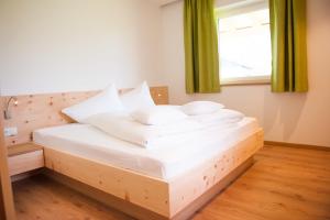 una camera con letto in legno e cuscini bianchi di Residence Hochwart ***S a Naturno