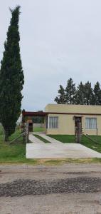 un edificio con un árbol delante de él en Casa con PILETA, PARRILLA y cochera cubierta en Chascomús
