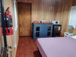 a room with a kitchen with a bed and a microwave at Refugios del Monte in Villa Yacanto