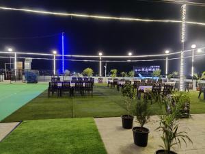 a tennis court with tables and chairs on a tennis court at Hotel Manas Plus in Khandwa