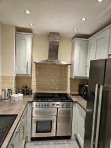 a kitchen with a stainless steel stove and white cabinets at Lister Park Bradford 2bed Detached Cottage House & Parking & Cinema Screen in Shipley
