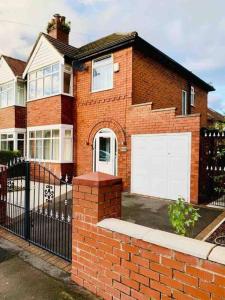 a brick house with two white garage doors at Immaculate 3-Bed Travel nest unavailable in Manchester