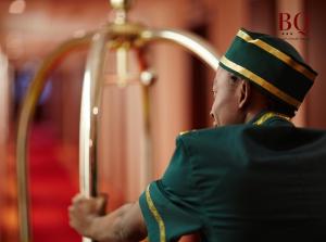 un hombre de uniforme verde tocando en un arpa en البندقية للأجنحة الفندقية بريدة BQ hotel suites en Buraidah