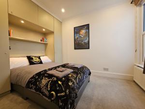 um quarto com uma cama com um cobertor preto e dourado em MAGICAL HARRY POTTER HOME IN WATFORD with FREE off-street PARKING em Watford