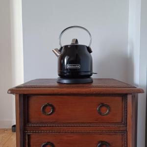 einen Wasserkocher mit schwarzem Tee auf einem Holztisch in der Unterkunft Le Banellou in Quimper