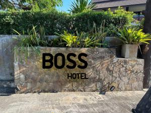 a sign for a boss hotel on a stone wall at BOSS HOTEL CHIANGMAl in Chiang Mai