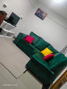 uma sala de estar com um sofá verde com almofadas coloridas em Tranquil 2 homes em Nanyuki