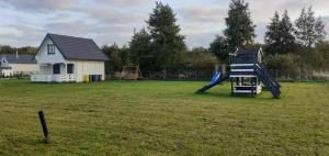 a playground with a slide in a yard with a house at Domek Arkadia in Gąski