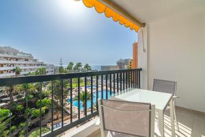 a balcony with a table and chairs and a view of a pool at Viña del Mar, Disfruta del Relax in Playa de las Americas