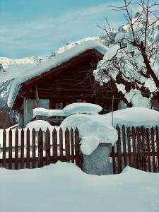a fence covered in snow next to a house at La Stalla in Vicosoprano