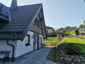 a white house with a black roof and a bench at Ferienhaus Naturregion Sieg bis 6 Personen in Windeck