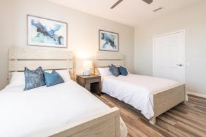 two beds in a bedroom with white walls and blue pillows at VistaCay Balcony near Pool Convention Ctr iDrive in Orlando