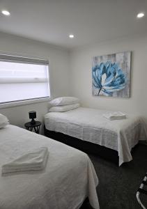 sypialnia z 2 łóżkami i obrazem na ścianie w obiekcie Redwood Apartments w mieście Rotorua