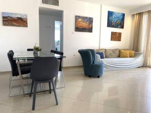 a living room with a couch and a table and chairs at Sunny 3BR Apartment Golf Residence in Eilat