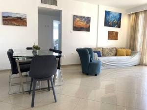 een woonkamer met een bank, een tafel en stoelen bij Sunny 3BR Apartment Golf Residence in Eilat