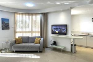 a living room with a couch and a flat screen tv at Sunny 3BR Apartment Golf Residence in Eilat