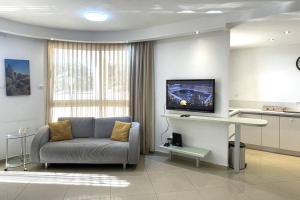 een woonkamer met een bank en een flatscreen-tv bij Sunny 3BR Apartment Golf Residence in Eilat