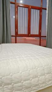 a large white mattress in a room with a window at Ashkara beach house in Al Ashkharah