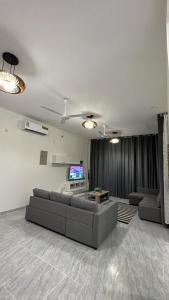 ein Wohnzimmer mit einem Sofa und einem TV in der Unterkunft Al Ashkhara Beach House in Al Sharqiyah